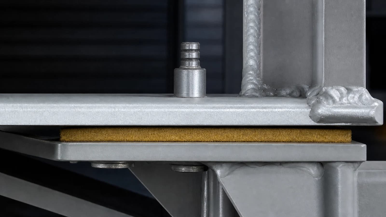 Close-up of Huck fasteners and a vibration damping pad at a suspension mounting