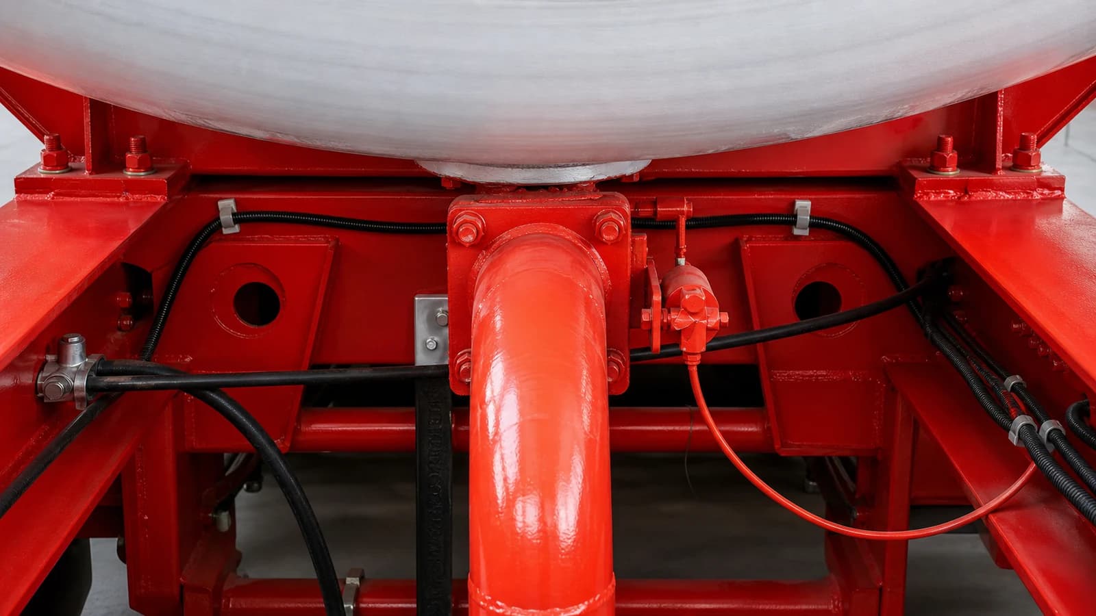 Underbody of a finished tanker showing the valve block and pipework routed along the frame, with the fittings and brand markings visible.